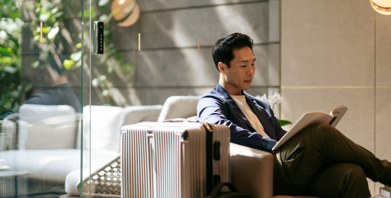 Upper class Asian male businessman reading a magazine in an airport lounge Upper class Asian male businessman reading a magazine in an airport lounge