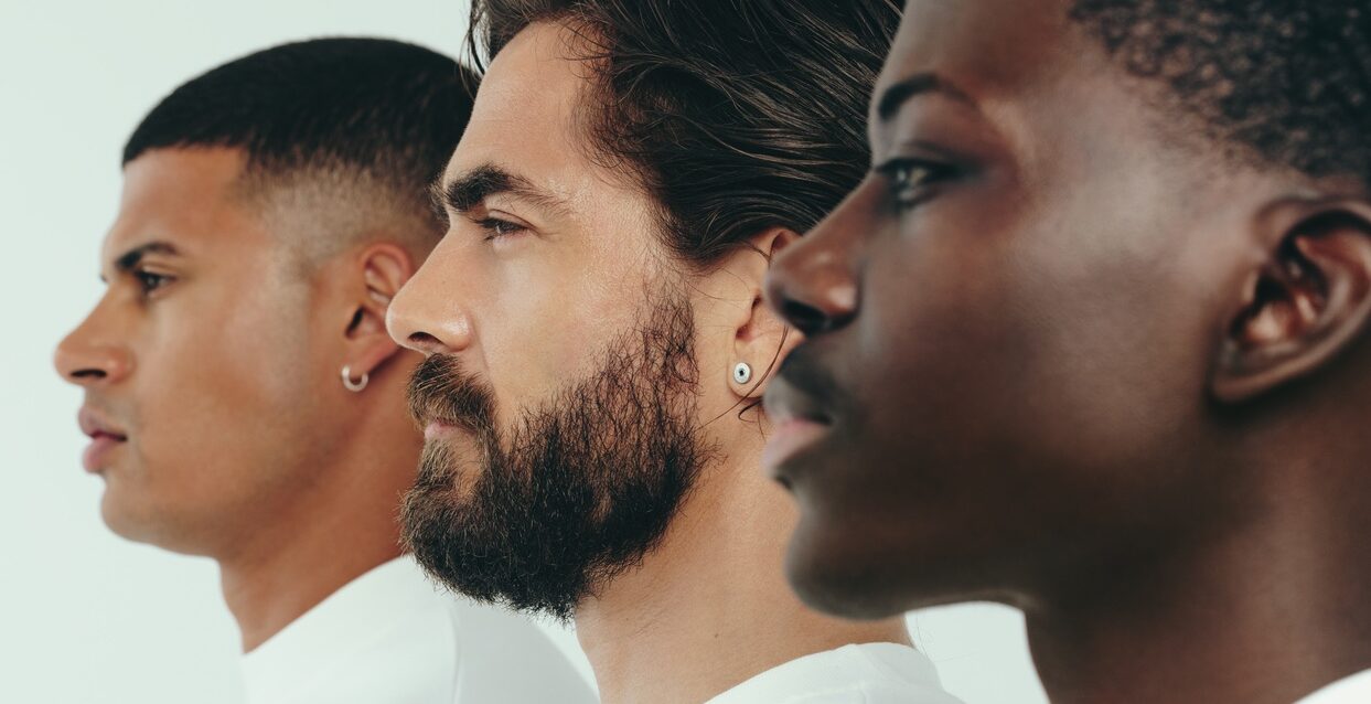 Three men with diverse skin tones standing together in a studio, showing the results of a consistent skincare routine