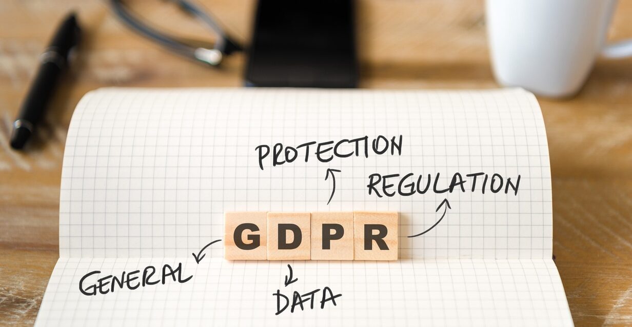 Closeup on notebook over wood table background, focus on wooden blocks with letters making GDPR General Data Protection Regulation text Closeup on notebook over wood table background, focus on wooden blocks with letters making GDPR General Data Protection Regulation text